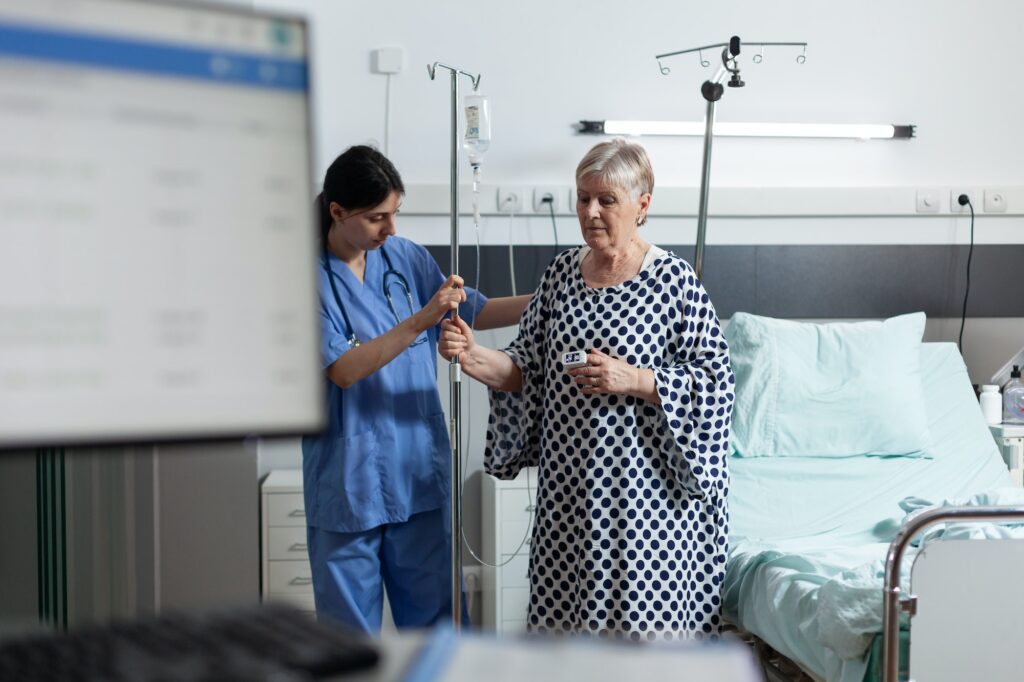 Sick senior woman carrying iv drip bag with help from medical nurse